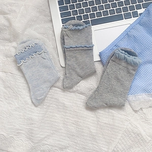 Detail of sweet bow-knot socks with ruffled edges in pastel blue and grey cotton