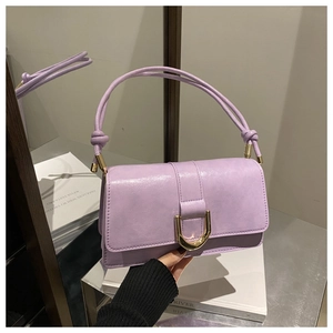 Detail of light purple leather handbag featuring a gold D-buckle and elegant knotted strap
