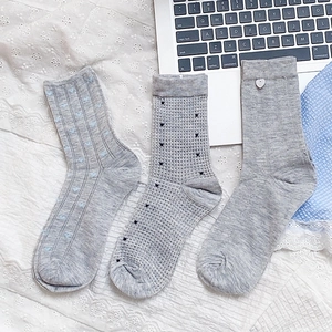 Three pairs of grey cotton crew socks with blue hearts and shell buttons on lace background