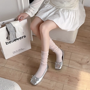 Close-up of silver ballet flats with bow detail and soft pink loose leg warmer socks
