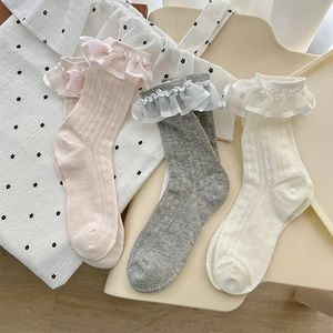Close-up of white, pink, and grey ruffle socks with delicate hollow flower knit texture