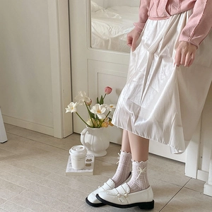 Gros plan de mocassins blancs avec perles et chaussettes en dentelle violette à volants