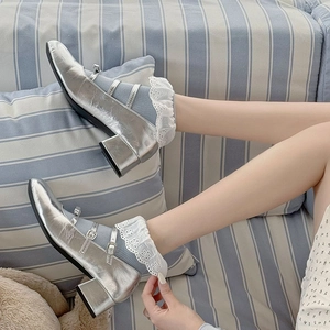 Detail of silver Mary Jane shoes with double straps and white lace edge grey socks
