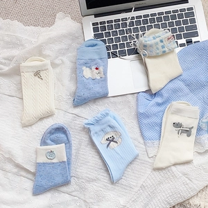 Detail of blue and white socks with bow accents and cute dog embroidery in a cozy setting