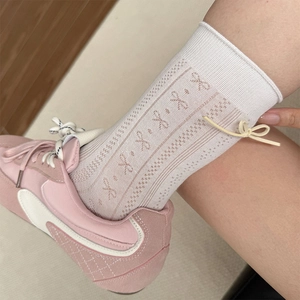 Detail of white mesh socks with hollow knit pattern and a yellow 3D bow on the side