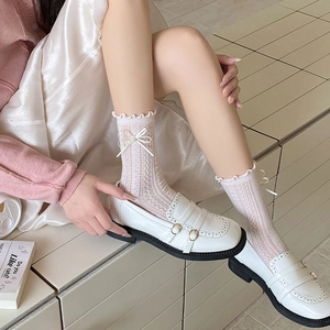 Détail de chaussettes roses en dentelle avec nœuds et mocassins blancs