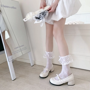 Detail of white dot lace socks with ruffled edges and silk bows paired with Mary Janes
