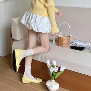 Detail of white mesh lace socks with wavy edges paired with yellow Mary Jane shoes