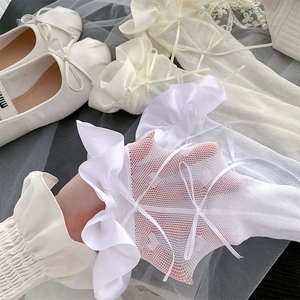 Detailsicht weißer Netzsocken mit herzförmigem Muster und Satinschleifen am Saum