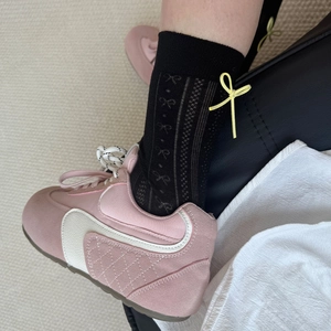 Detail of black mid-calf socks with yellow bow accent and pink patchwork sneakers