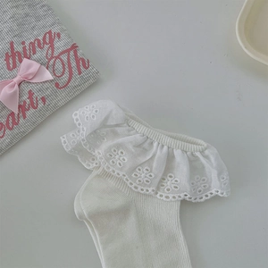 Detailed view of white cotton socks with intricate floral lace trim and ribbed knit texture