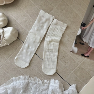 Detailed view of white mesh crew socks with bow patterns and ruffled edges on lace