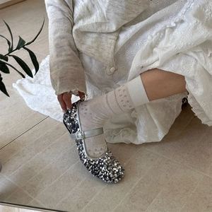 Silver sequin Mary Jane shoes paired with white lace socks and hollow floral patterns