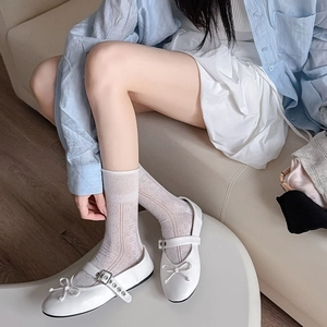 Close-up of white Mary Jane flats with bow detail and lace hollow mid-calf socks
