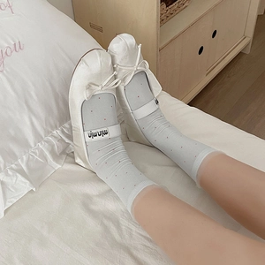 Detail of ballet flats with lace ruffle socks on a white bed for a soft girl aesthetic