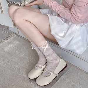 Detail of pink lace mesh socks with white bow accent and pearl strap Mary Jane shoes