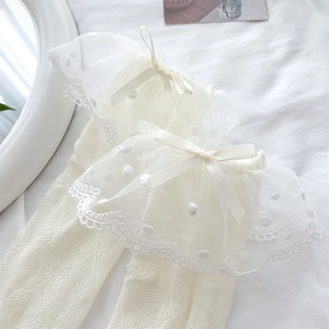 Detailed view of white polka dot lace cuffs with satin bows on mesh knee-high socks
