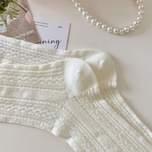 Close-up of white mesh knit socks with delicate hollow wave patterns and lace edges