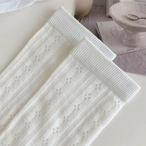 Detail of cream knit socks with hollow floral patterns and ribbed texture for women