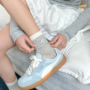 Detail of grey ribbed crew socks with blue heart bow embroidery and soft fabric texture