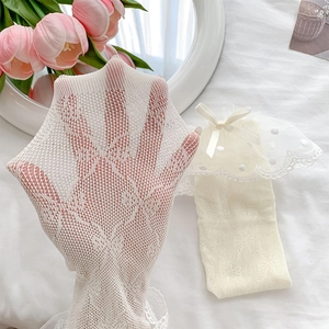Close-up of white lace mesh socks with polka dot pattern, embroidery, and satin bow detail