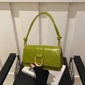 Olive green faux leather shoulder bag with golden U-shaped buckle on a stylish chair