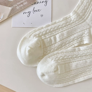 Close-up of white mesh knit socks with wave patterns and hollow breathable details