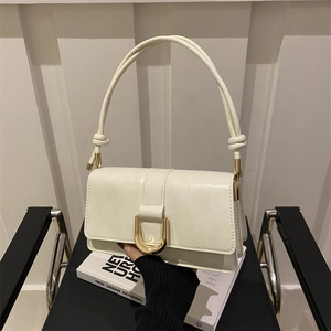 Chic cream white leather crossbody handbag with gold buckle on a black chair
