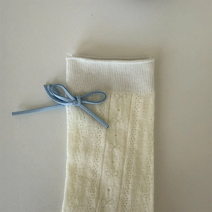Detail of cream white knit socks with blue suede bow and hollow mesh floral patterns