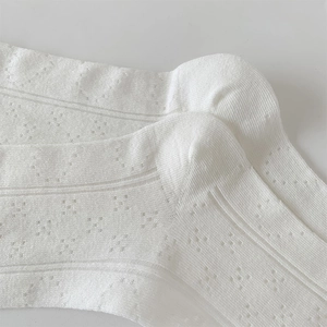 Detail of white hollow lace socks with delicate floral mesh pattern for breathability