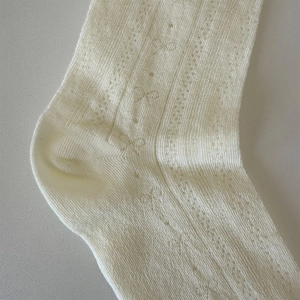 Detail showing hollow pointelle pattern and sweet bow texture on cream white knee high socks