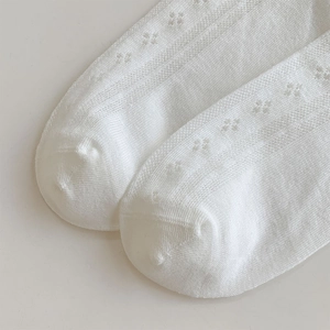 Macro shot of white knitted hollow-out socks with fine mesh texture and flat toe seams