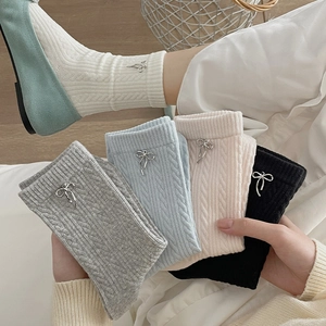 Detailed knit texture of mid-calf socks with elegant silver metal bow accents
