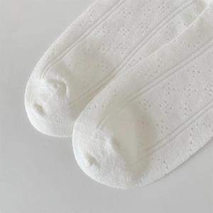 Detail of white ballet-style mesh socks with vertical ribbing and hollow-out knit patterns