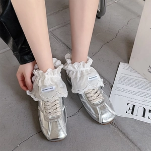Silver ballet sneakers paired with white lace ruffle socks and bow ribbon straps