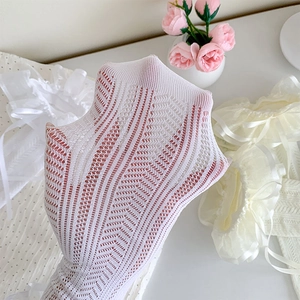 Detailed macro view of white Lolita lace socks with mesh pattern and ribbon bow decor