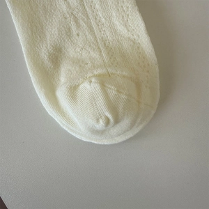 Detailed macro view of cream-colored knit mesh socks with breathable weave pattern