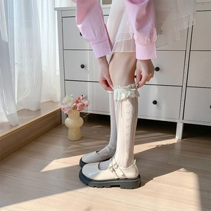 Dettaglio di calze al ginocchio in pizzo bianco con cuori e scarpe Mary Jane beige