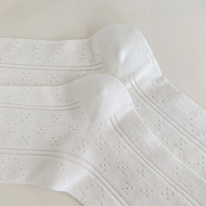 Close-up of white breathable hollow knit socks with delicate jacquard stripe patterns