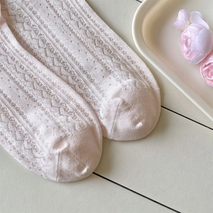 Détail de chaussettes bébé rose clair en maille pointelle avec motifs ajourés