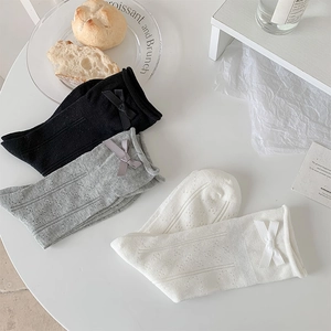 Close-up of ballet-style mesh socks with bow accents in black, white, and grey colors