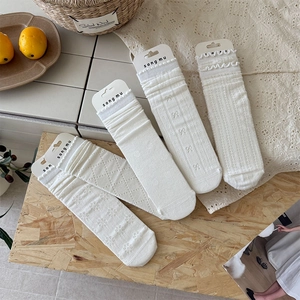 Detail of five pairs of white cotton socks featuring lace, dots, bows, and mesh patterns