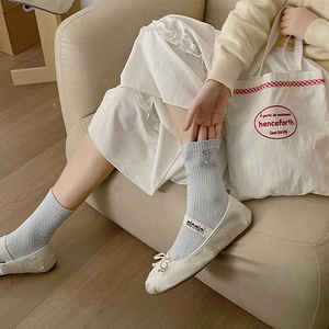 Detail of light blue cable knit socks featuring a silver metal bow accent on the side