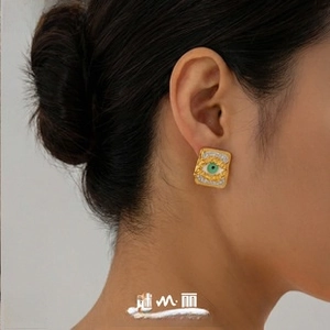 Close-up of a vintage square gold earring featuring a turquoise evil eye and white zircons