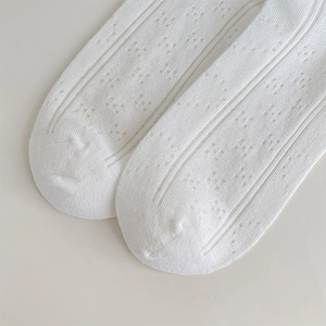 Close-up of white knit socks with vertical stripes and hollow out texture details