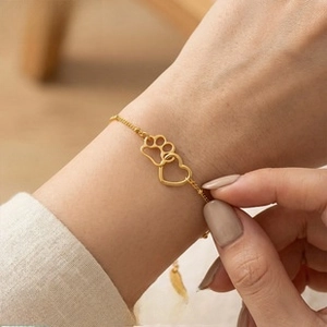 Close-up of gold 18k plated bracelet featuring interlocking heart and paw print charms