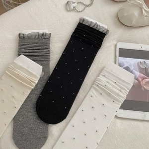 Detail of four-color dot socks with delicate lace trim on a white fabric background