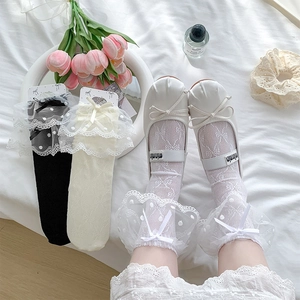 Detail of sweet lace ruffle socks with polka dots and bows on soft white bedding