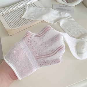 Close-up of white hollow-out mesh socks showing breathable texture and pattern