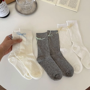 Detailed shot of mesh hollow-out socks featuring delicate ribbon bows and knit patterns